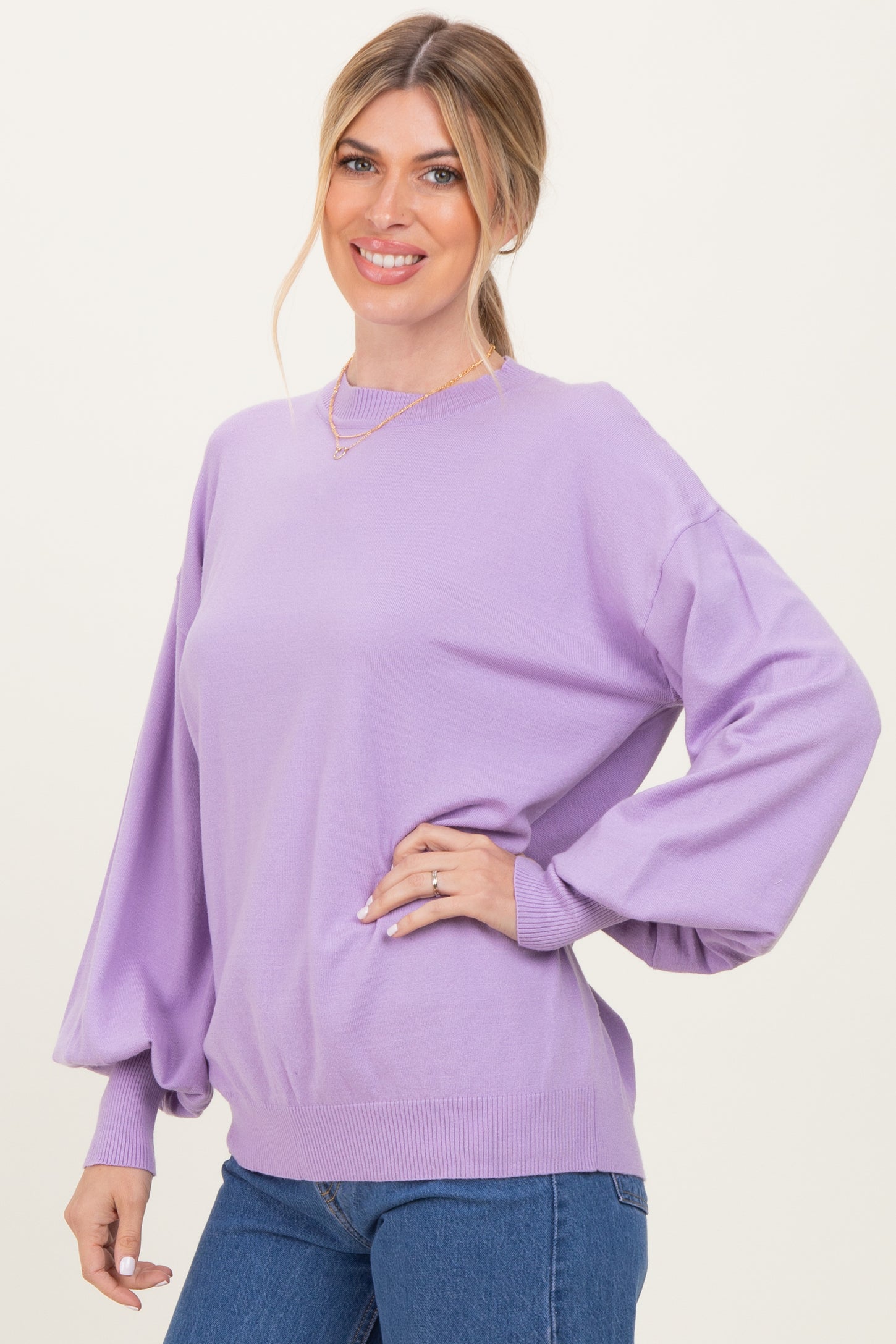 woman wearing a lilac oversized sweater with puffed sleeves and a round neckline, styled with blue jeans