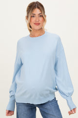 woman wearing a light blue oversized maternity sweater with balloon sleeves and a visible baby bump