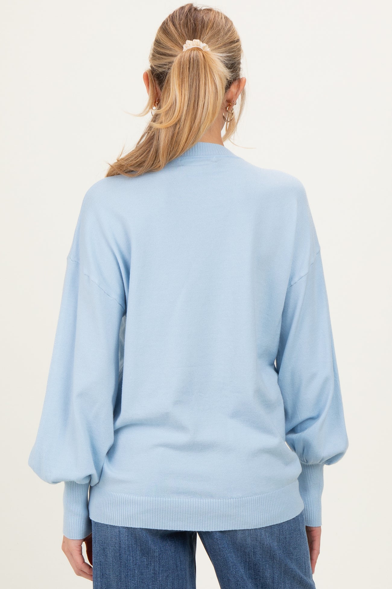 woman wearing a light blue oversized maternity sweater with puffed sleeves, viewed from the back
