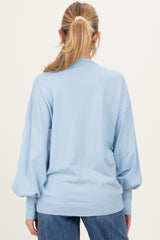 woman wearing a light blue oversized maternity sweater with puffed sleeves, viewed from the back