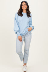 woman wearing a light blue oversized sweater with balloon sleeves and distressed light wash jeans
