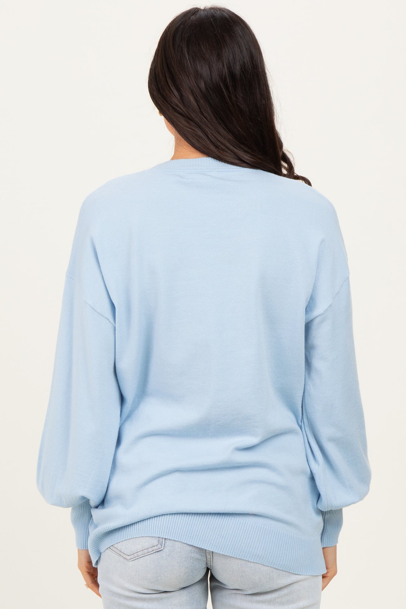 woman wearing a light blue oversized sweater with balloon sleeves, shown from the back