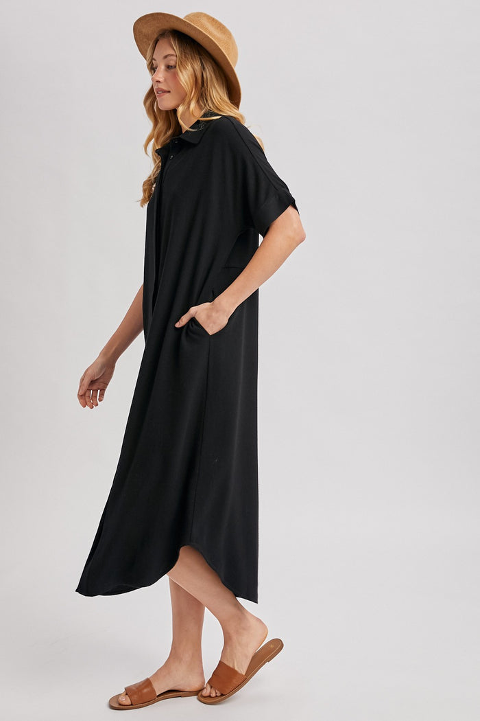 woman wearing a black midi dress with side pockets and a hood, paired with a straw hat and sandals