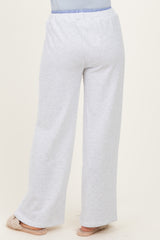 woman wearing light grey wide-leg lounge pants with an elastic waistband and light blue accent, standing with back to camera