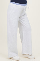 woman wearing light gray maternity sweatpants with a blue waistband and a visible baby bump