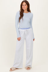 woman wearing a light blue long sleeve top and gray wide-leg sweatpants with a drawstring waistband