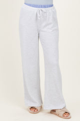 woman wearing light gray lounge pants with a drawstring waistband and a relaxed fit, paired with fuzzy slippers