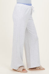 woman wearing light gray wide-leg sweatpants with an elastic waistband and drawstring detail, paired with cozy slippers