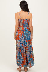 woman wearing a back view of a colorful floral maxi dress with spaghetti straps and a tiered skirt