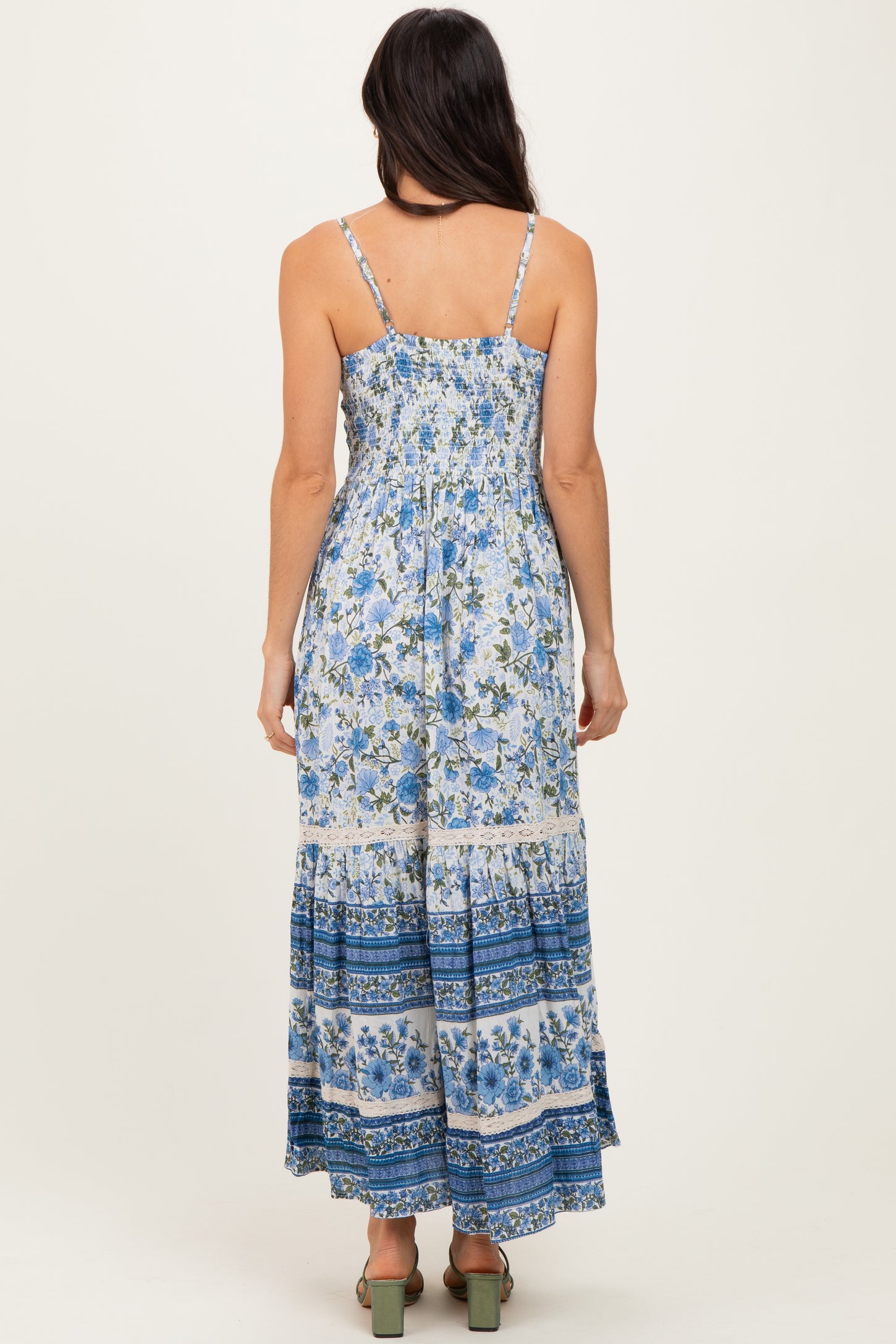 woman wearing a floral maxi dress with blue and white patterns and a smocked bodice, shown from the back