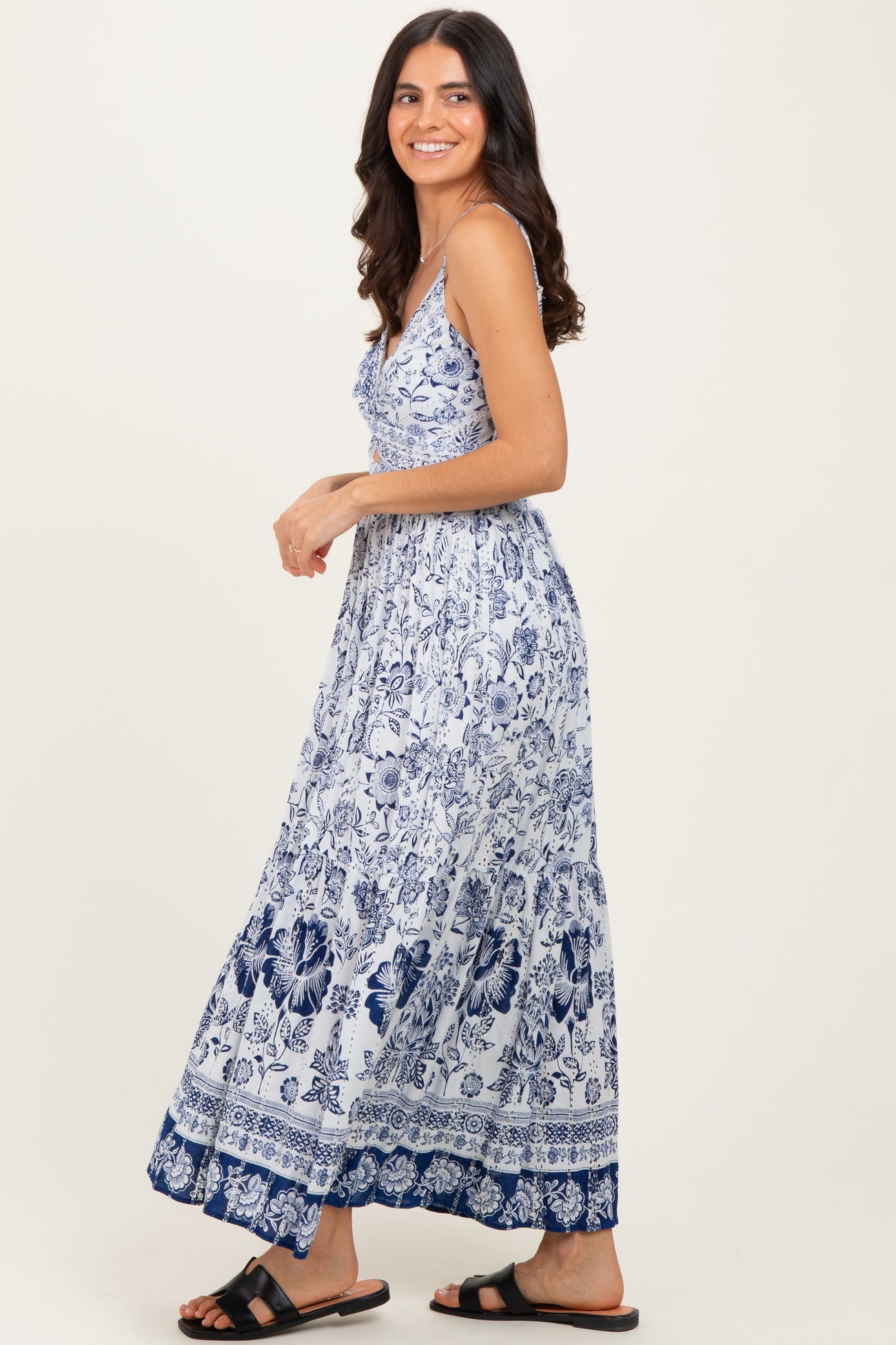 woman wearing a white and navy blue floral maxi dress with spaghetti straps and a flowing skirt