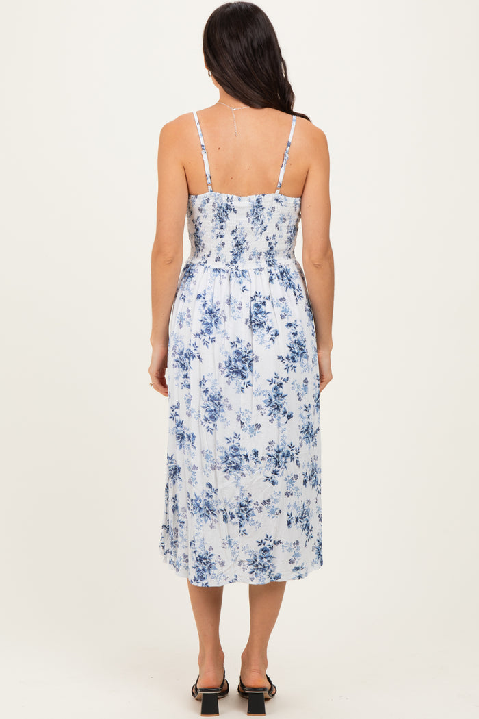 woman wearing a blue and white floral midi dress with adjustable spaghetti straps and a smocked back