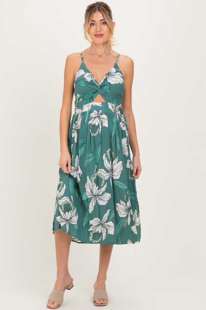 woman wearing a green floral print maternity dress with a twisted front and sleeveless design
