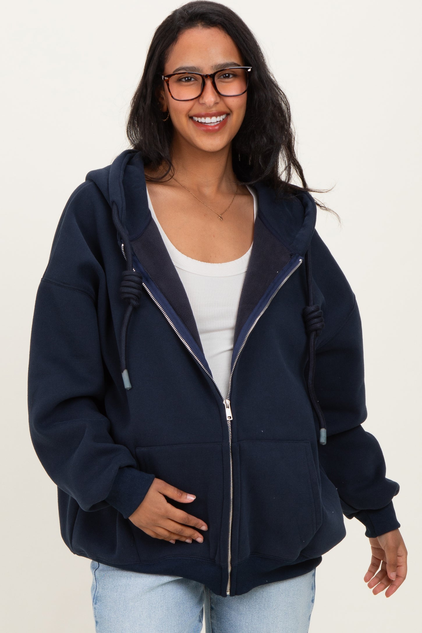 woman wearing a navy blue zip-up maternity hoodie with a relaxed fit and gray interior, holding her baby bump