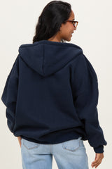 woman wearing a navy blue oversized maternity hoodie with a hood and a relaxed fit, seen from the back
