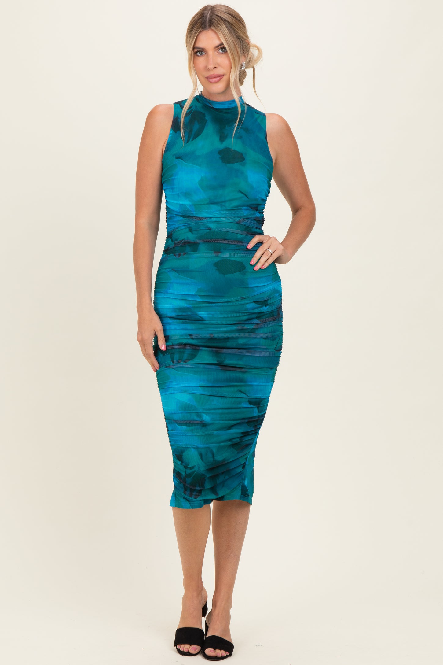 woman wearing a teal sleeveless midi dress with ruching details and a fitted silhouette