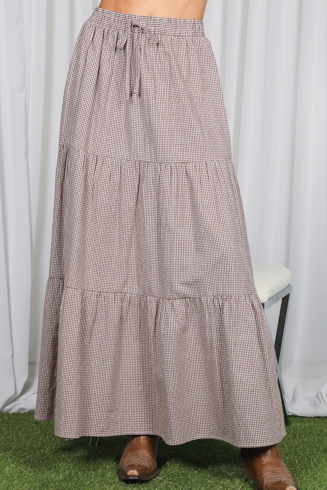 woman wearing a brown and white gingham tiered maxi skirt with an elastic waistband and drawstring detail