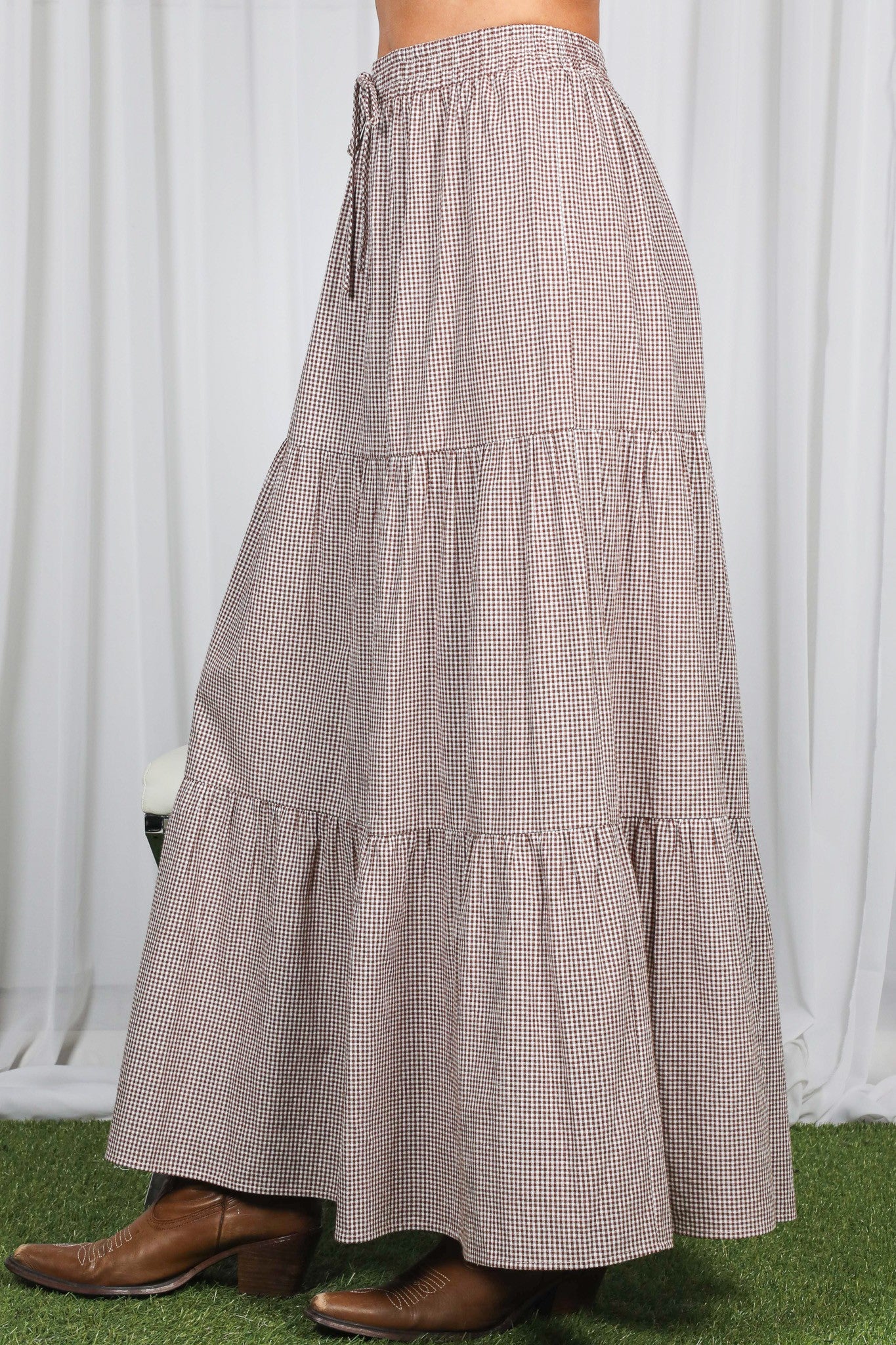 woman wearing a brown and cream checkered tiered maxi skirt with an elastic waistband and drawstring detail
