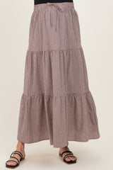 maternity wear in a brown and white checked maxi skirt with tiers and an adjustable tie waist, model wearing it