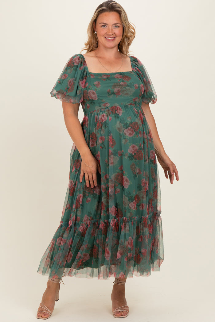 woman wearing a green floral maternity plus dress with puff sleeves and a tiered skirt, showing her baby bump