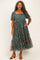 woman wearing a green floral midi dress with puff sleeves and a tiered skirt, styled with brown heeled sandals