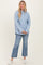 woman wearing a light blue striped button-up shirt and distressed flare jeans with white sneakers