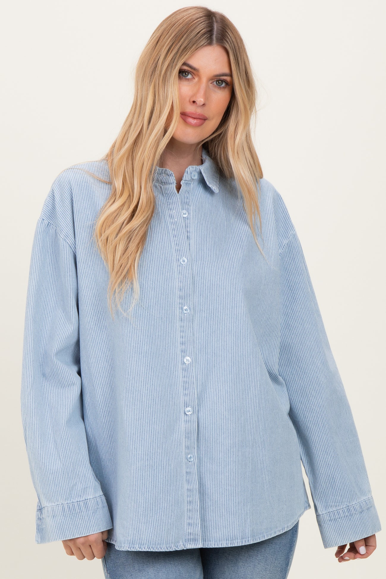 woman wearing a light blue striped oversized button-up shirt with long sleeves