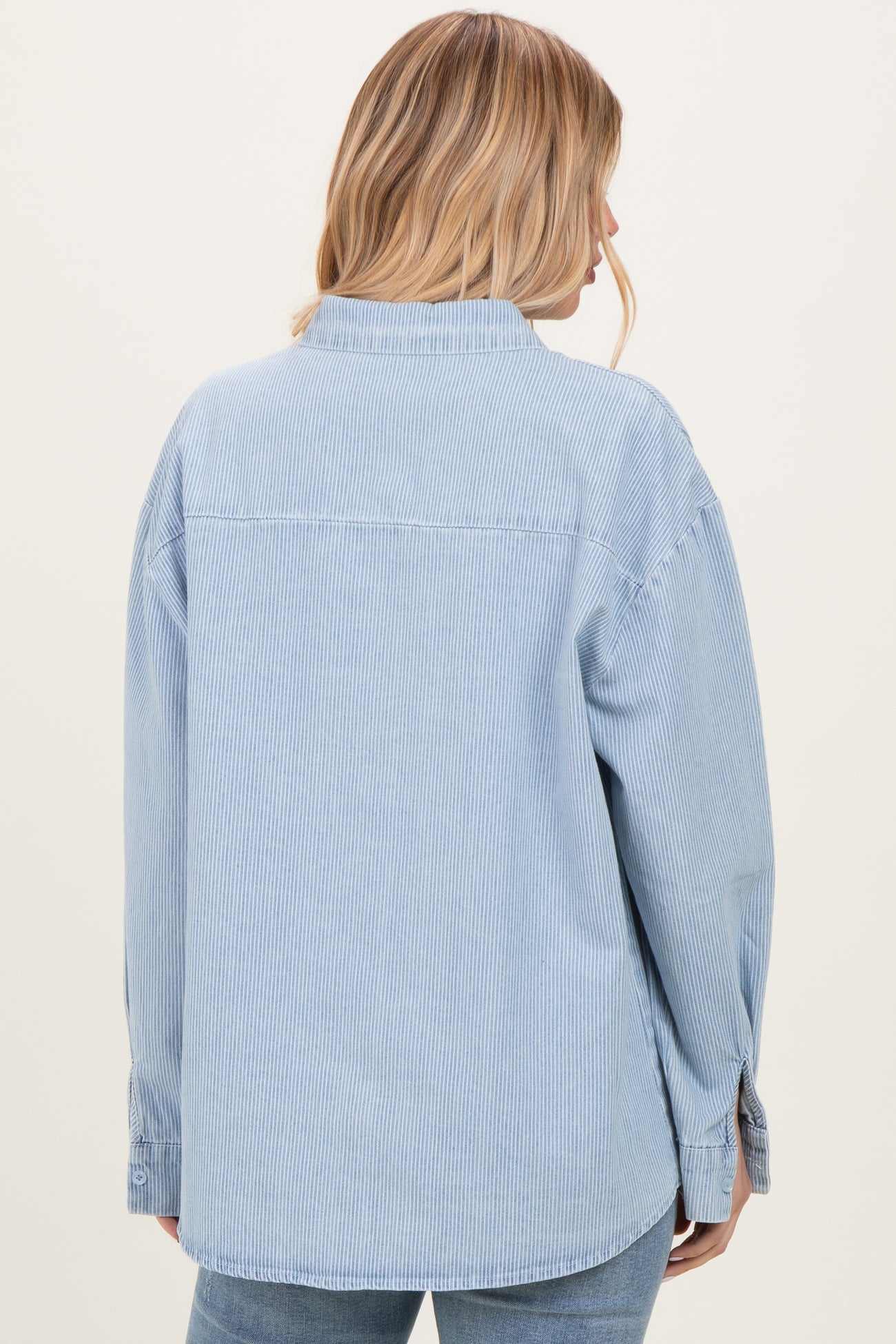 woman wearing a light blue striped oversized shirt, view from the back with long sleeves and relaxed fit