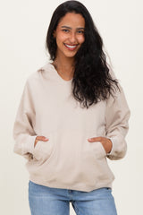 woman wearing a beige maternity hoodie with a v-neck and front pockets, smiling at the camera