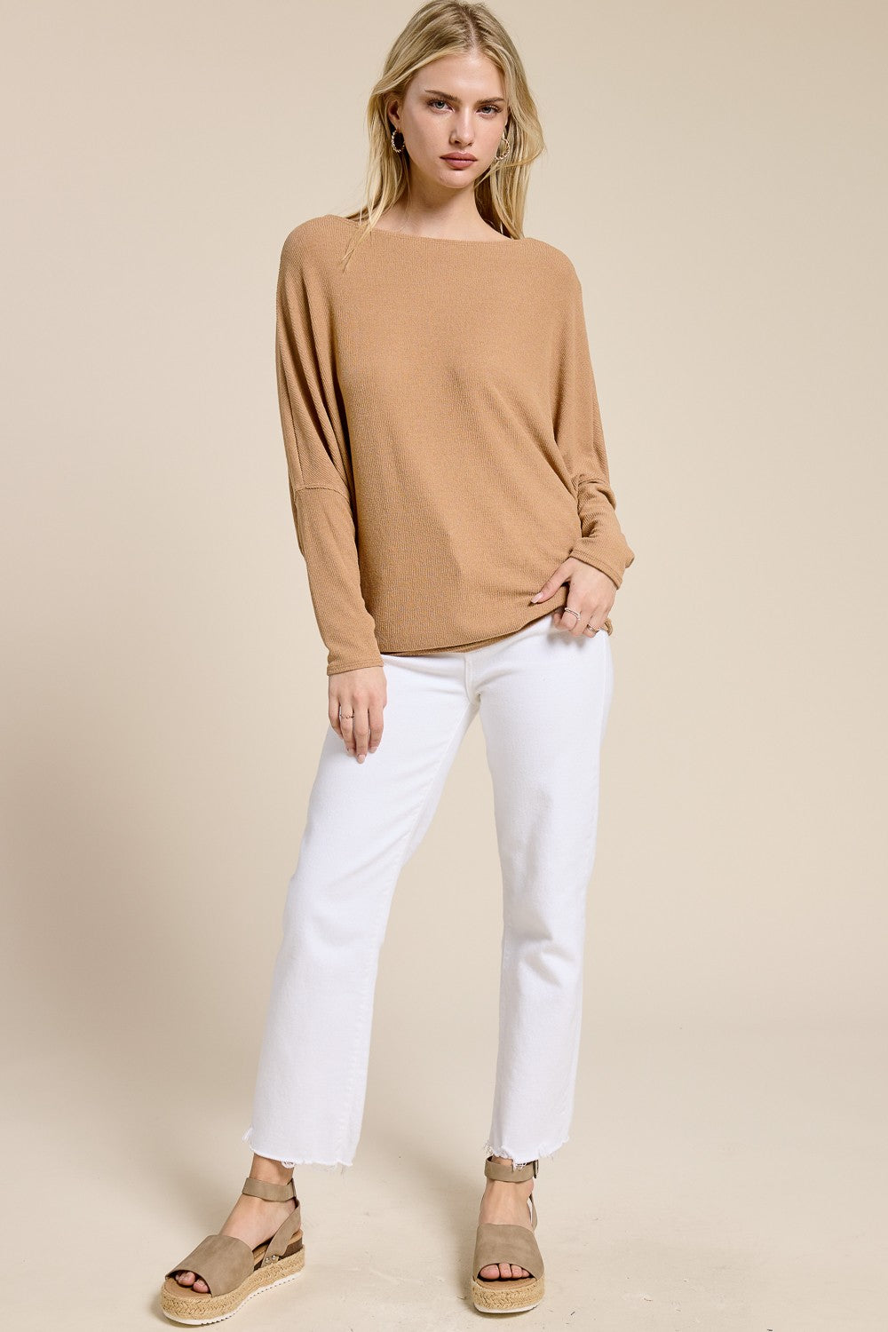 woman wearing a beige long sleeve top and white wide-leg jeans with tan espadrille sandals