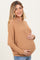 woman wearing a tan oversized maternity sweater and holding her baby bump