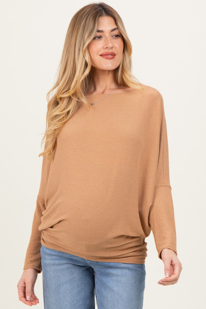 woman wearing a light brown maternity top with a relaxed fit and long sleeves, showcasing her baby bump