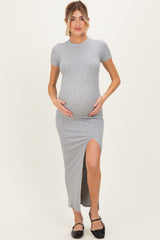 woman wearing a grey maternity maxi dress with a side slit and holding her baby bump