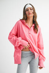woman wearing a bright pink oversized pullover with a collar and long sleeves, paired with gray leggings