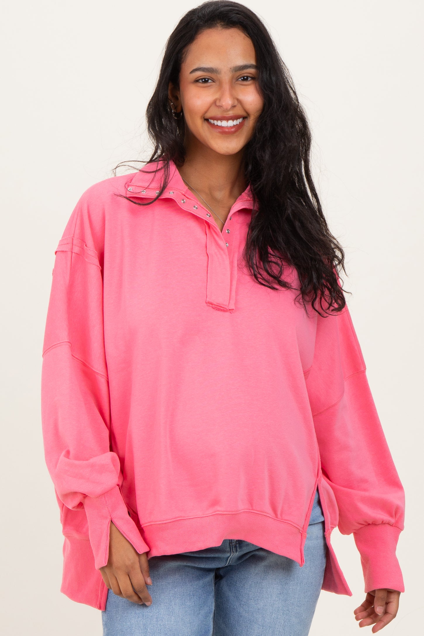 woman wearing a pink maternity sweatshirt with a collar and long sleeves, smiling at the camera