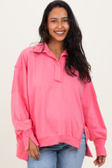woman wearing a pink maternity sweatshirt with a collar and long sleeves, smiling at the camera