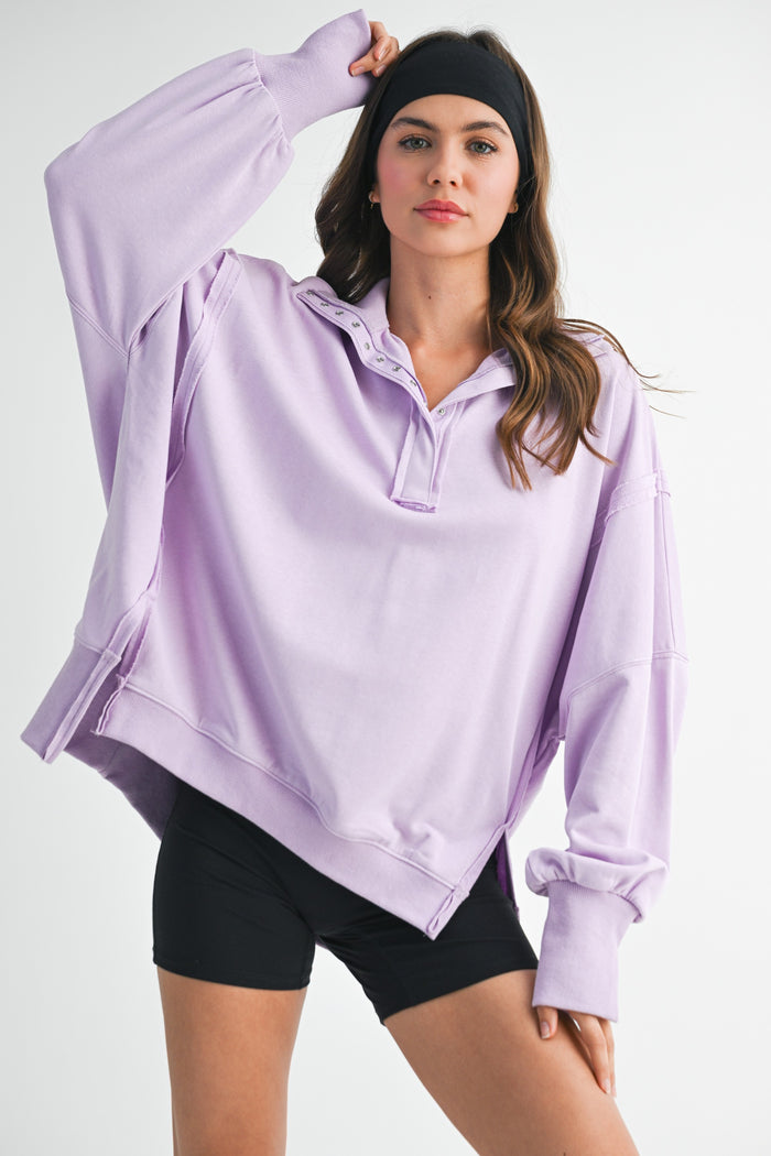 woman wearing a lavender oversized pullover sweatshirt with a half zipper and black shorts