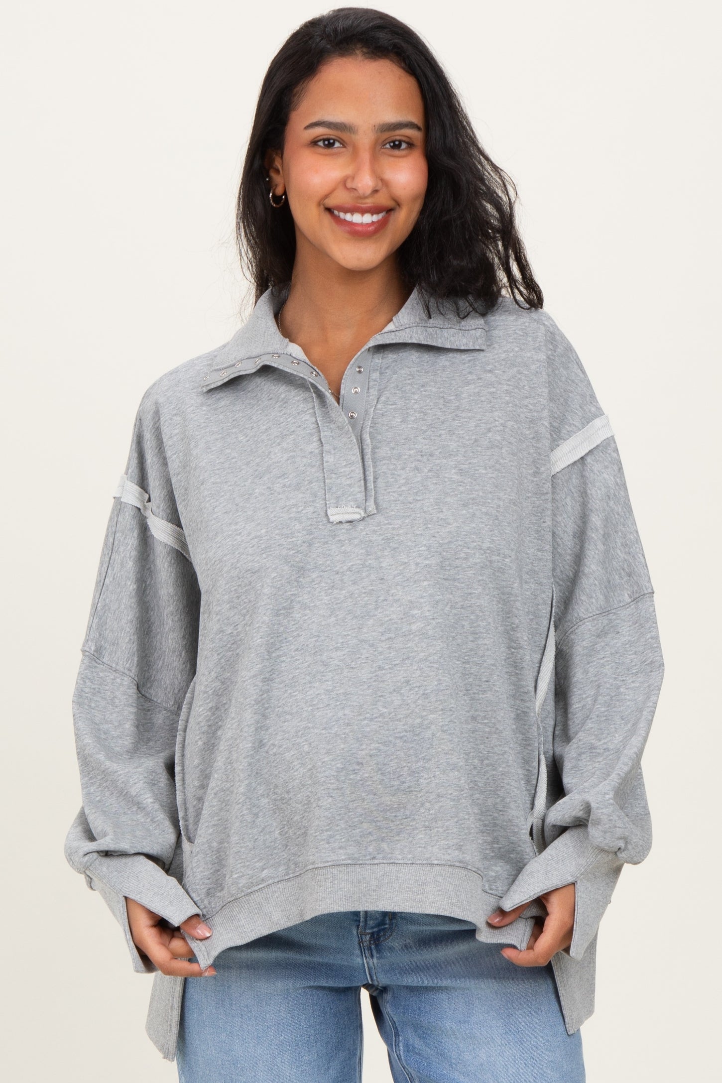 woman wearing a gray maternity pullover with a collar and long sleeves, showing her baby bump