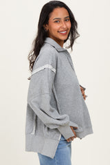 woman wearing a grey maternity sweatshirt with shoulder detail and holding her baby bump