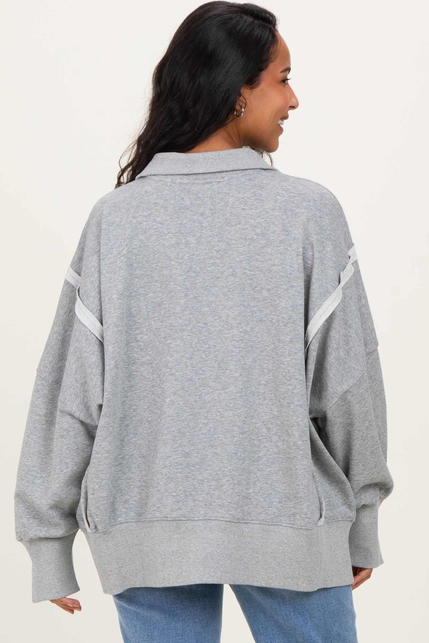 woman wearing a grey maternity oversized sweatshirt with contrasting stripes and a relaxed fit, displaying her baby bump