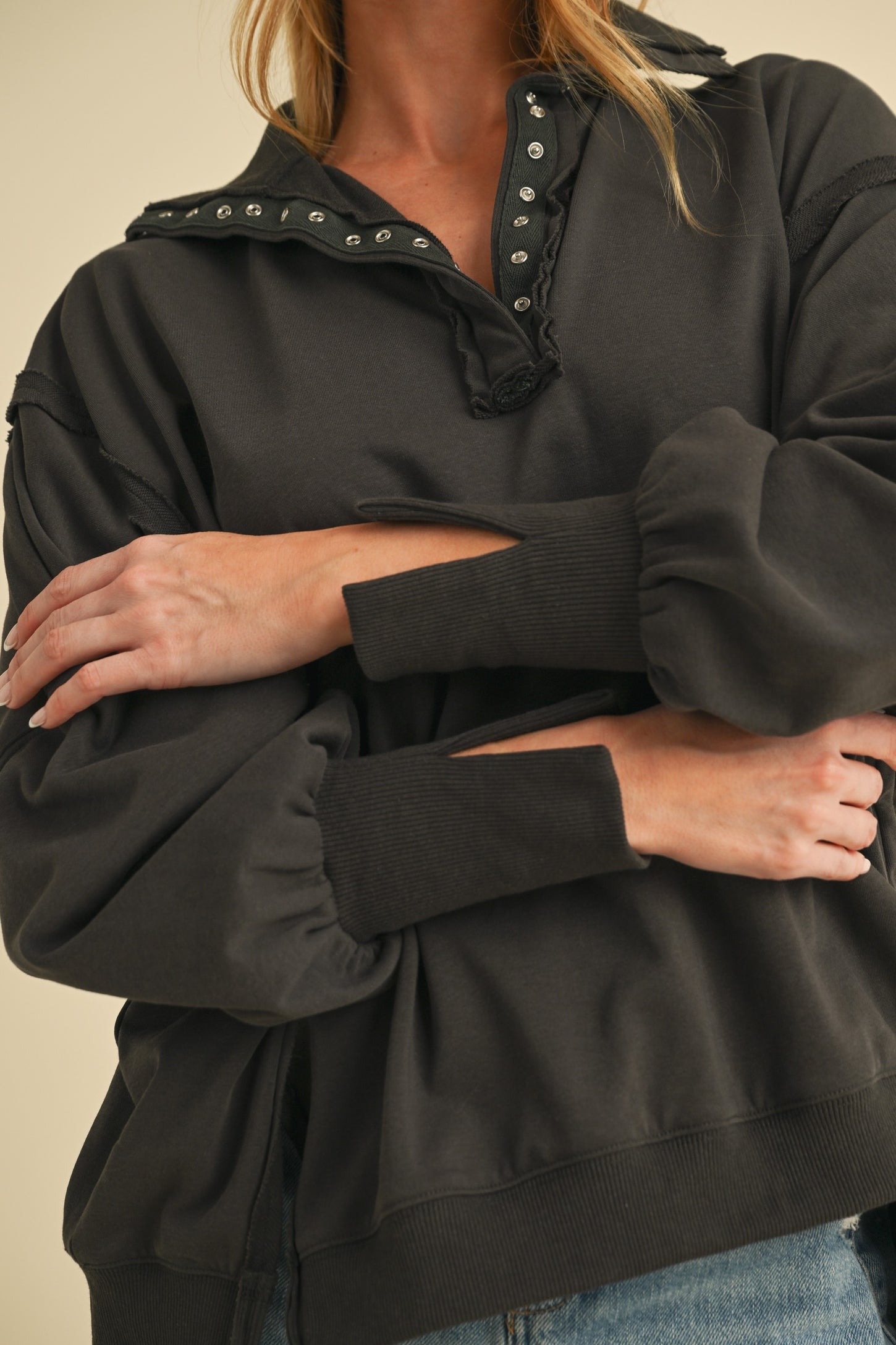 woman wearing a black oversized pullover sweatshirt with a henley collar and puff sleeves