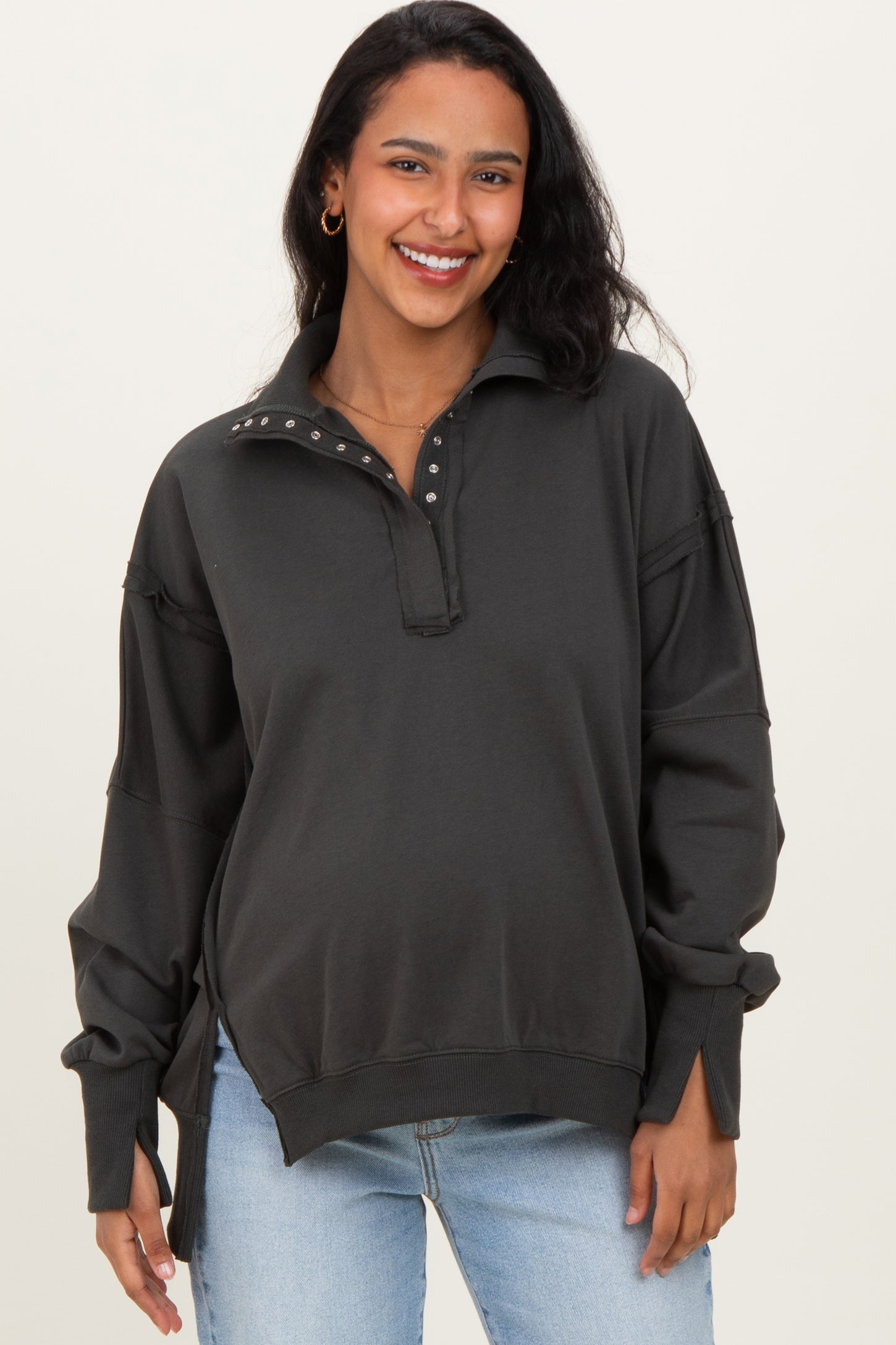 woman wearing a dark grey maternity sweatshirt with a collared neckline and button details, smiling at the camera