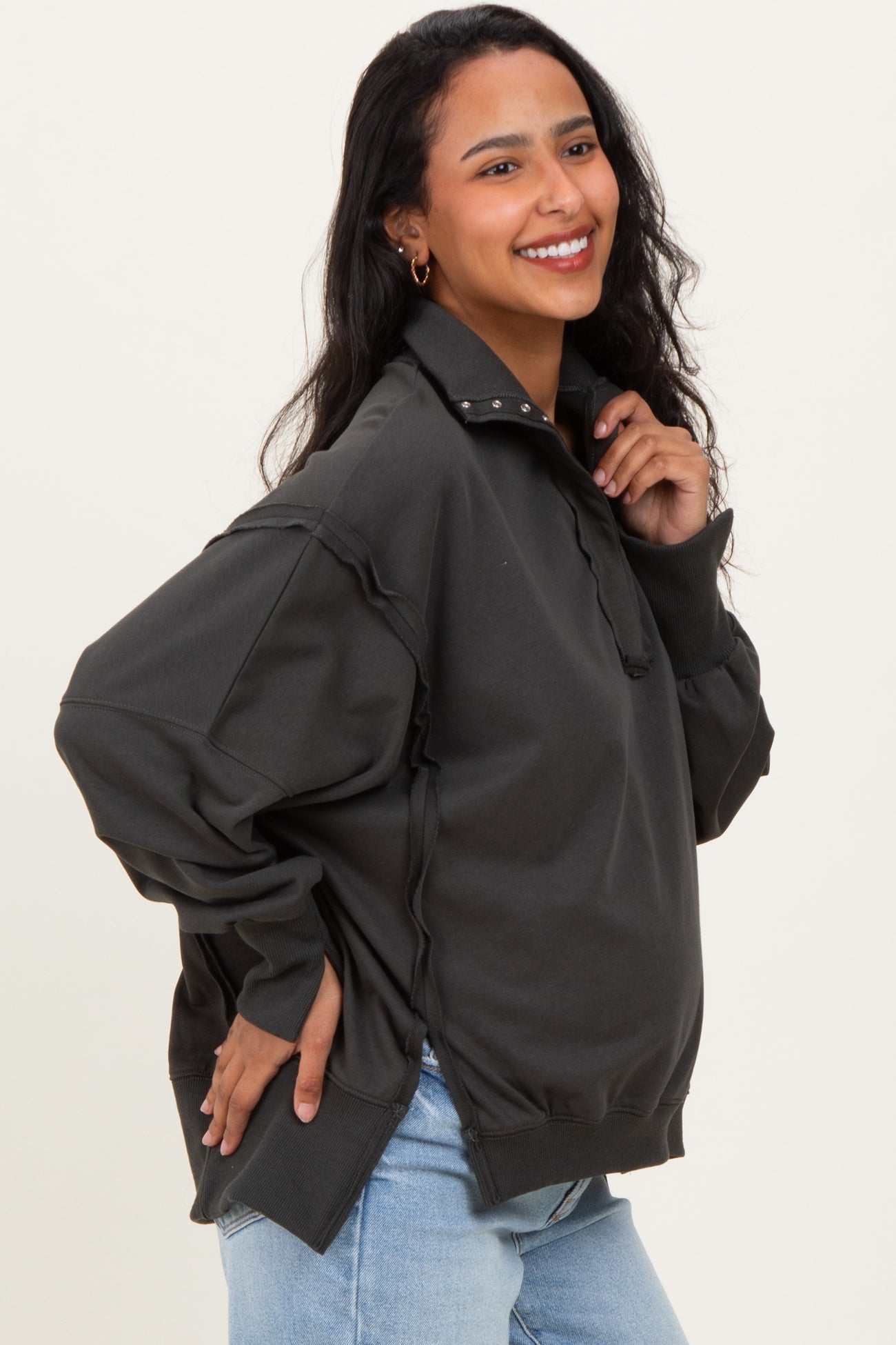 woman wearing a dark gray maternity pullover sweatshirt with a half zipper and relaxed fit, showing baby bump