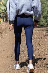 woman wearing navy blue fitted leggings with a high waist and walking on a trail