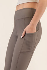 woman wearing tan high-waisted leggings with a side pocket and ribbed texture