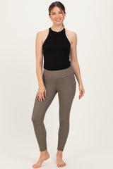 woman wearing a black halter neck maternity top and brown ribbed maternity leggings with side pockets