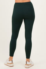 woman wearing dark green high-waisted leggings and white athletic shoes, viewed from the back