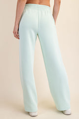 woman wearing light green wide-leg sweatpants, viewed from the back, featuring a comfortable elastic waistband