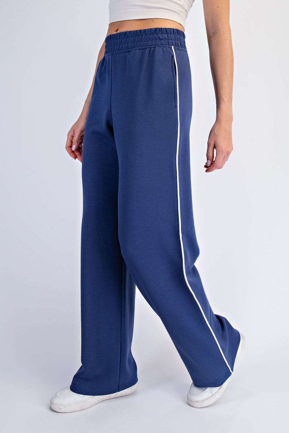 woman wearing navy blue wide-leg pants with a white side stripe and an elastic waistband