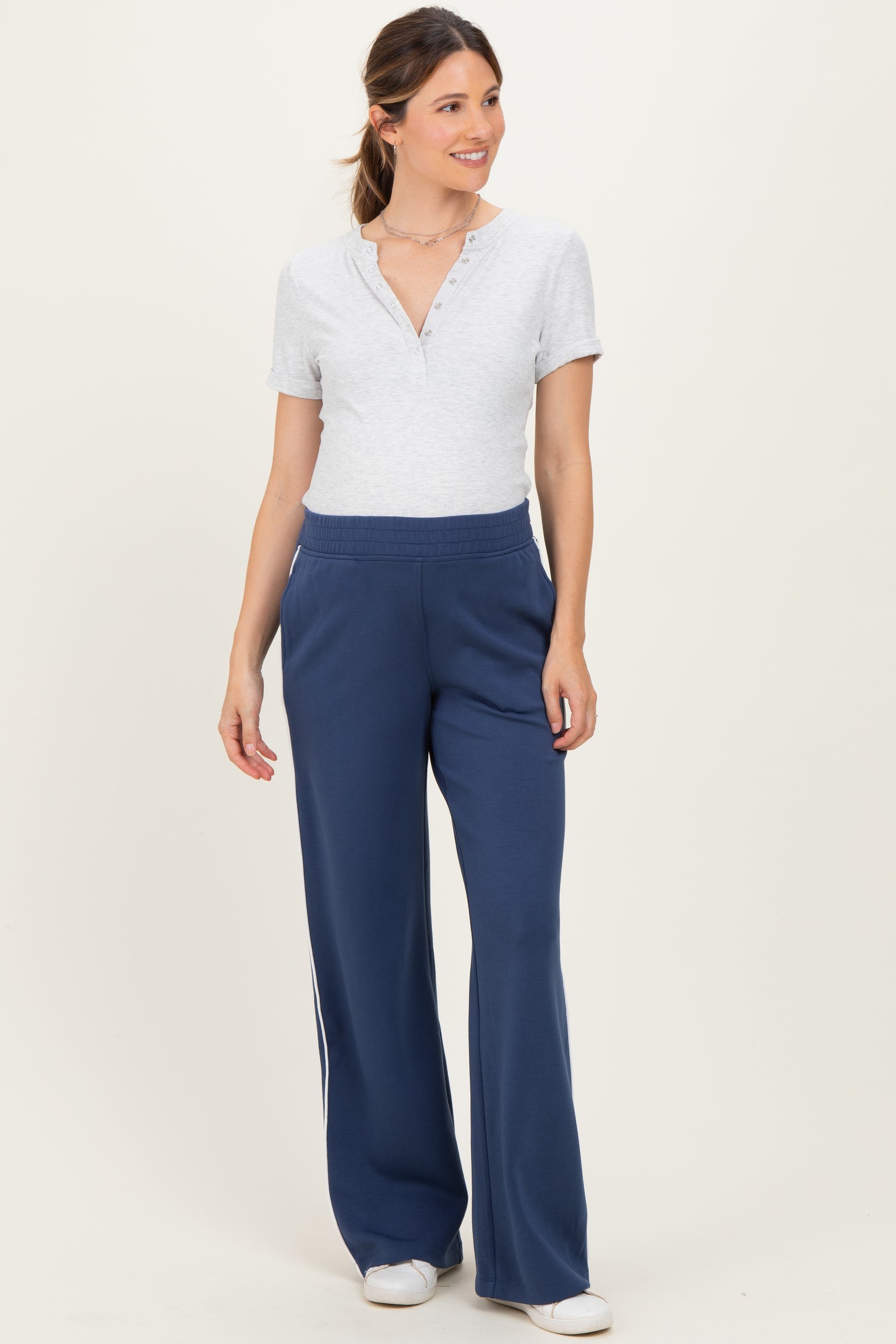 woman wearing a light gray short sleeve henley top and navy blue wide-leg maternity pants